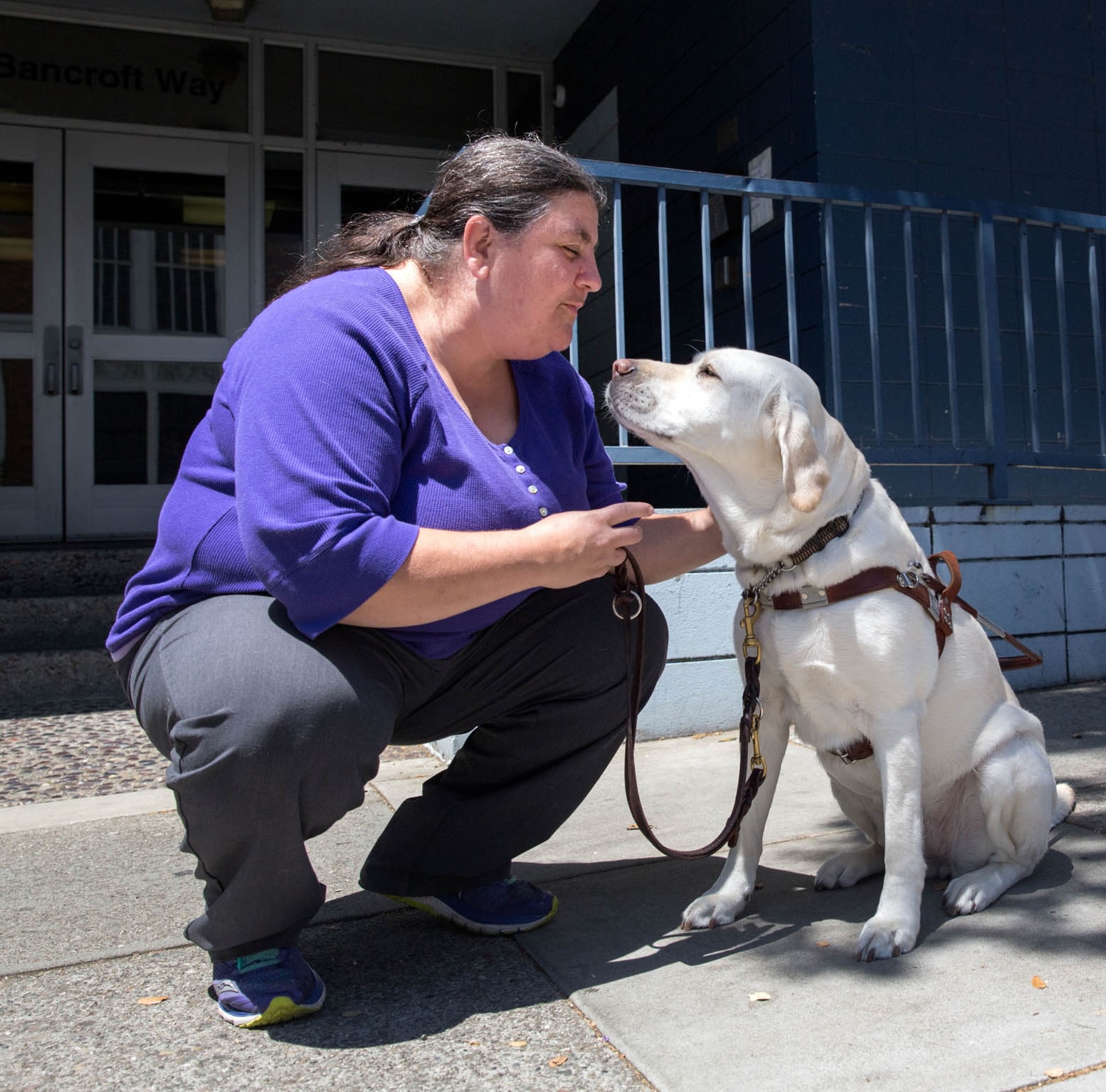 Lucy and her dog Frances, a white lab, are looking at each other endearingly