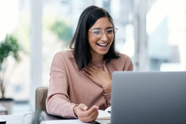 A smiling, relieved developer wearing glasses looking at her laptop screen with a hand placed over her chest in joy and satisfaction after solving an issue.
